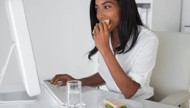 Woman eating sandwich with a glass of water